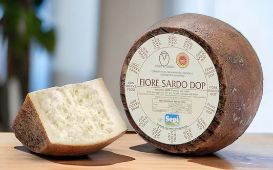 Fiore Sardo Stagionato cheese wheel with a slice showcasing its texture and label details.