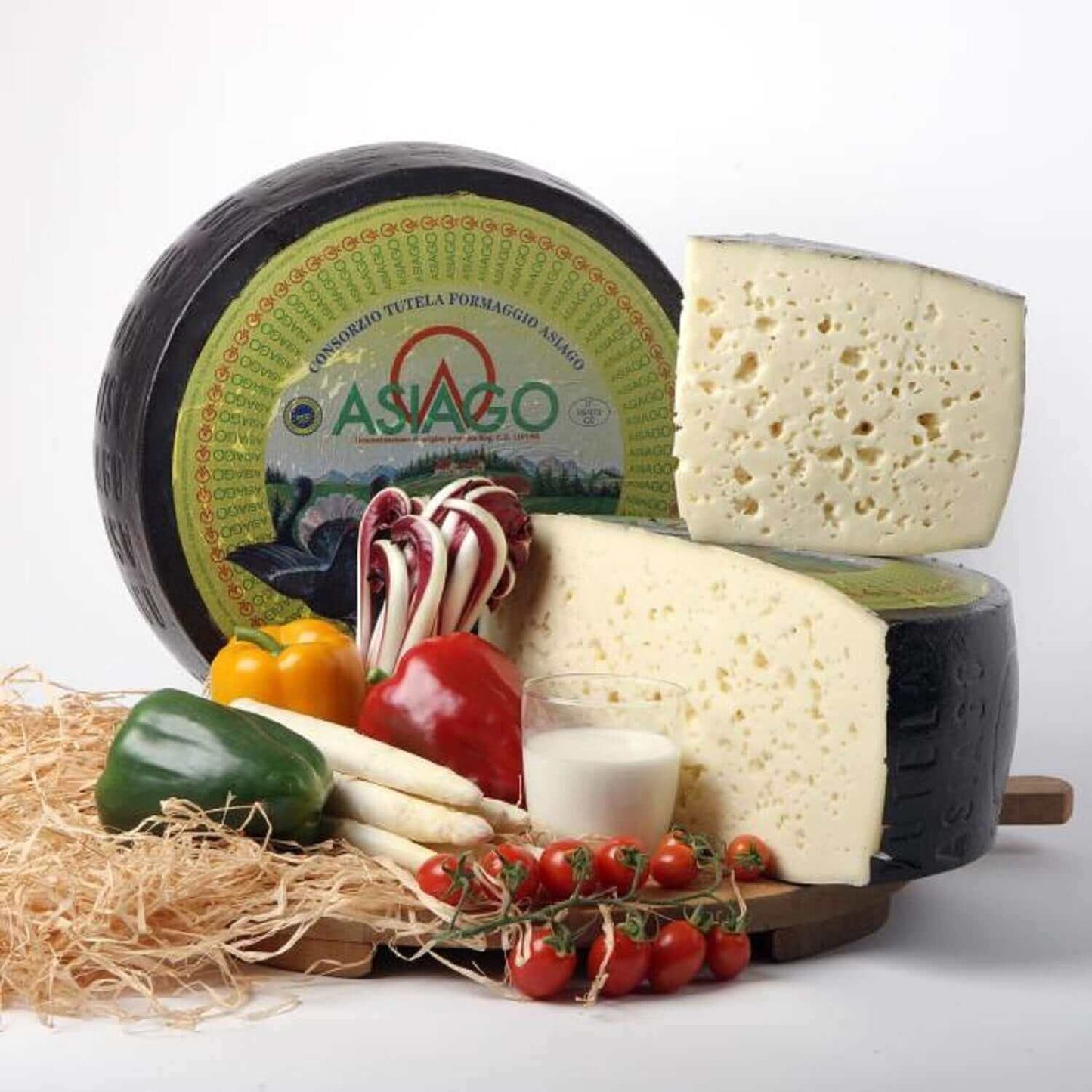 Asiago Crosta Nera cheese with peppers, tomatoes, and other ingredients on a rustic display.
