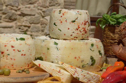Formaggio Farcito Siciliano con rucola, pomodoro secco e olive, in un ambiente rustico.