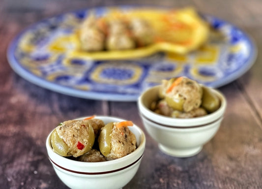 Olive Verdi Ripiene con Mollica in small bowls on a decorative plate, showcasing a delicious Italian appetizer.