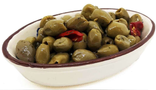 Olive verdi grandi schiacciate alla calabrese in a bowl, with green olives, chili, and spices.