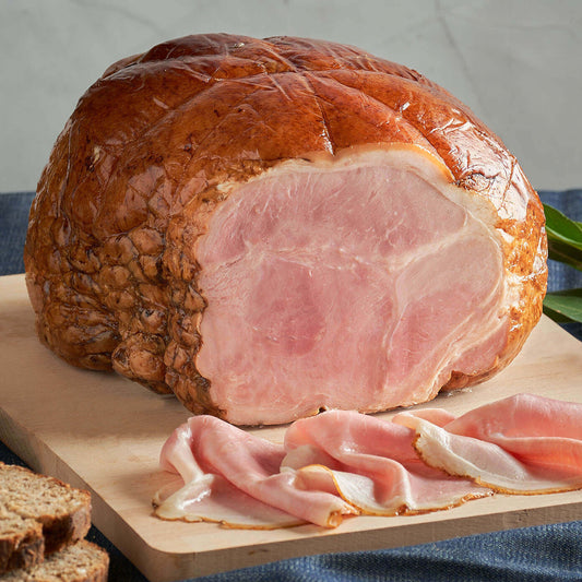 Prosciutto cotto alla brace, artisan ham with tender, flavorful meat on a wooden cutting board.