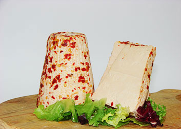 Ricotte Stagionate Salate cheese with chili on a wooden board featuring fresh greens.