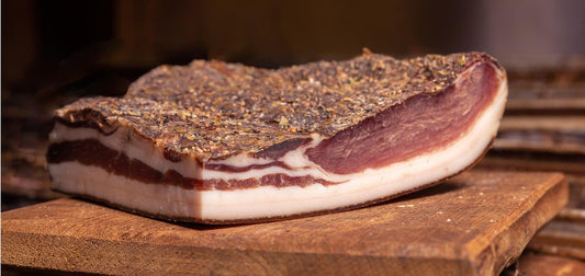 Speck Alto Adige IGP displayed on a wooden cutting board, highlighting its unique flavor and texture.