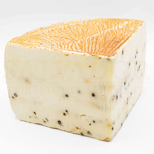 Block of Ulisse Pepato cheese aged in olive oil with black pepper, weighing approximately 6 kg, showcasing a rustic appearance.