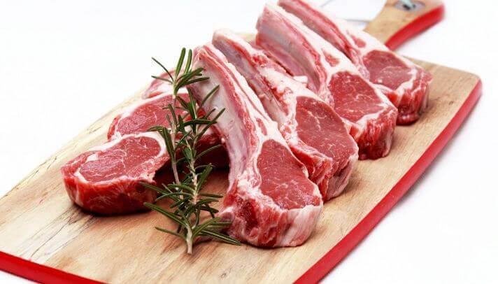 Agnello Semibrado in quarti su un tagliere di legno con rametto di rosmarino, prodotto fresco e non congelato.