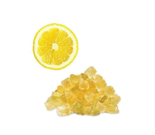 Sliced lemon and pile of candied ginger against a white background