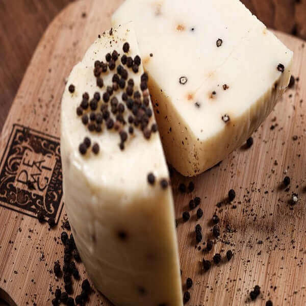 Formaggio Stagionato Siciliano al Pepe Nero, un formaggio pecorino con pepe nero su un tagliere di legno.
