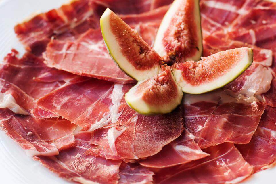 Slices of prosciutto ham served with fresh fig halves.