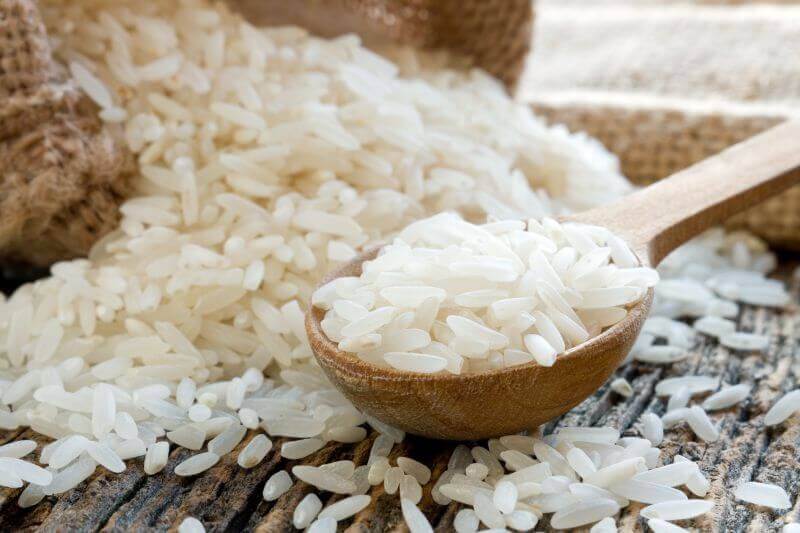 Riso di Sibari - Arborio di Calabria 1 kg in a wooden spoon surrounded by grains of rice.