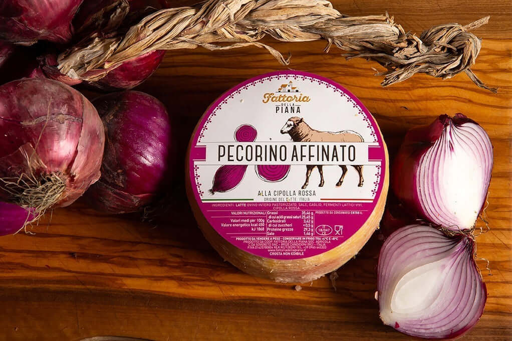 Pecorino alla Cipolla Rossa di Tropea cheese wheel on wooden board with red onions