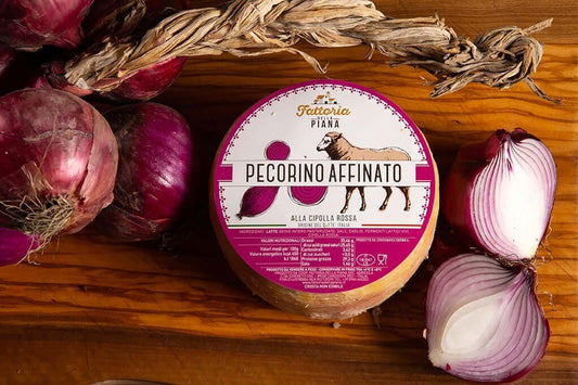 Pecorino alla Cipolla Rossa di Tropea cheese wheel on wooden board with red onions