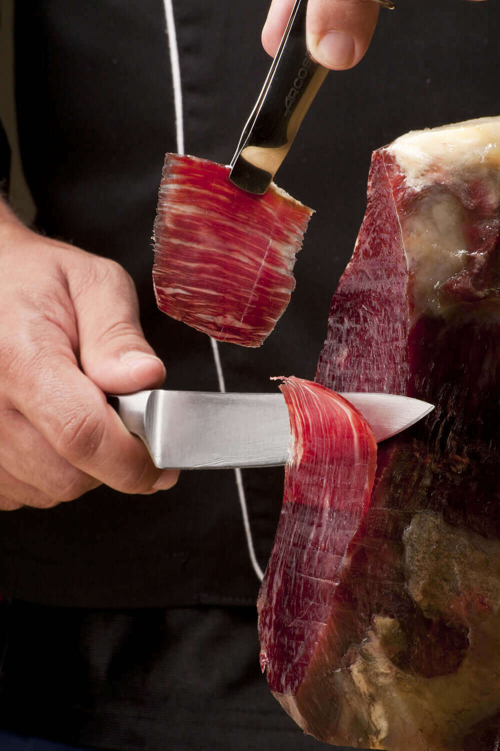 Slicing premium cured meat with precision knife skills for a gourmet culinary experience.